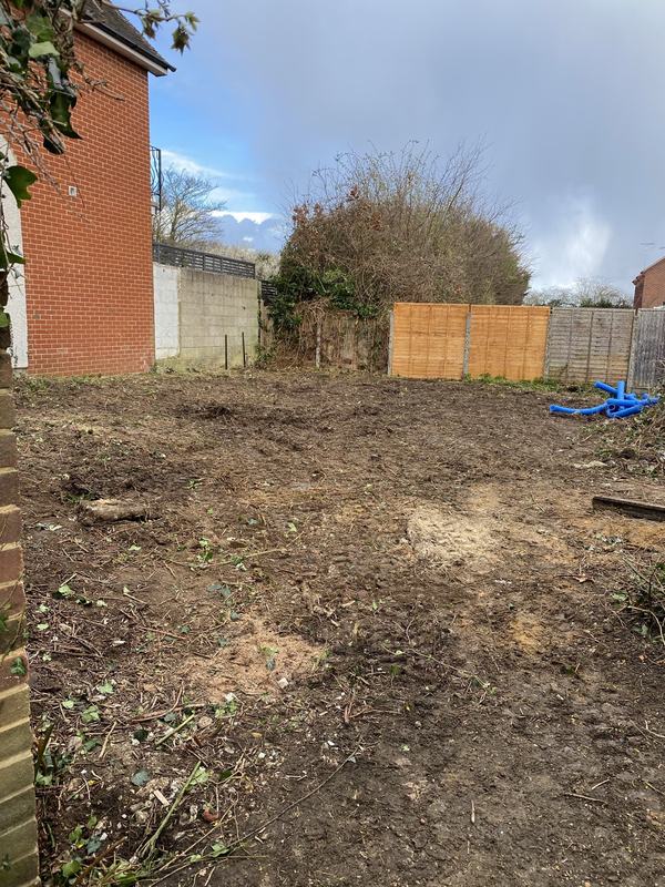 Fully cleared garden plot of bare soil between fences, ready for the next stage