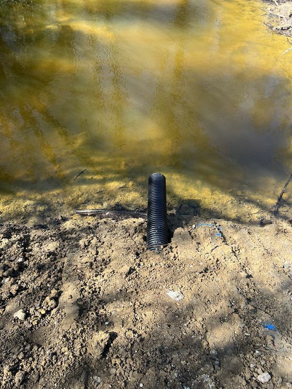 Drainage outfall pipe discharging into a pond