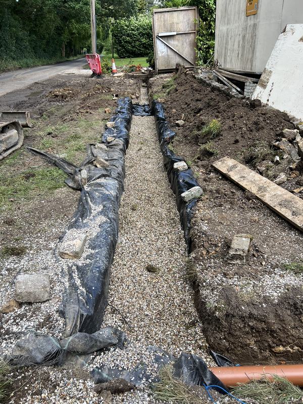 The same drainage trench backfilled with gravel between membrane-lined sides