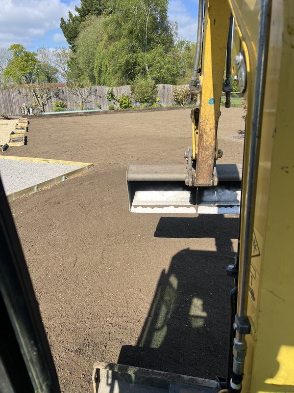 Mini digger bucket resting on a smooth, levelled garden